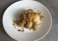 White plate topped with golden fried potato balls and sautéed onions, close-up.
