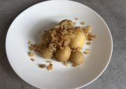 White plate topped with golden fried potato balls and sautéed onions, close-up.